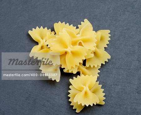 Arrangement of Raw Farfalle Pasta closeup on Black Stone background. Top View