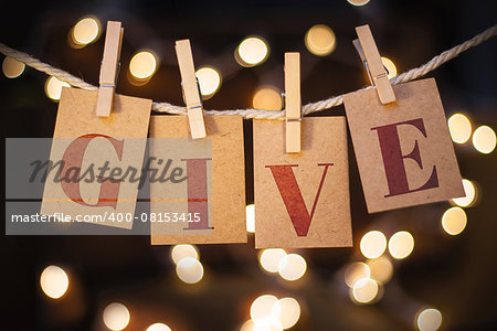 The word GIVE spelled out on clothespin clipped cards in front of glowing lights.