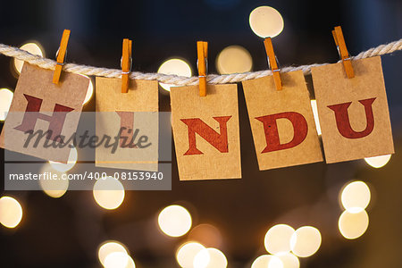 The word HINDU printed on clothespin clipped cards in front of defocused glowing lights.