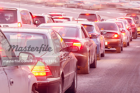 Cars stand before the trafficlight on the central city streets at sunset time.