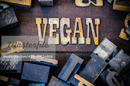 The word VEGAN written in rusted metal letters surrounded by vintage wooden and metal letterpress type.