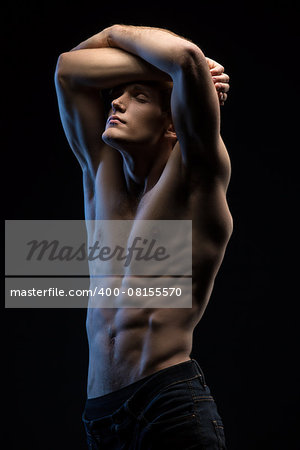 Portrait of handsome red-haired athlete topless at the studio on a black background in low key