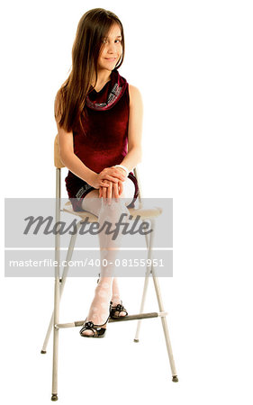 Attractive Teen Girl with Long Brown Hair in Purple Dress Sitting on Chair and Posing isolated on white background