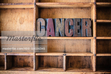 The word CANCER written in vintage wooden letterpress type in a wooden type drawer.