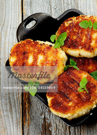 Delicious Homemade Meat Cutlets in Black Saucepan with Basil closeup on Rustic Wooden background. Top View