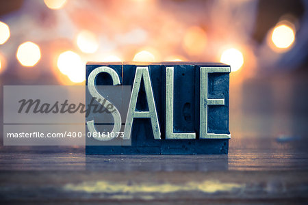 The word SALE written in vintage metal letterpress type on a soft backlit background.