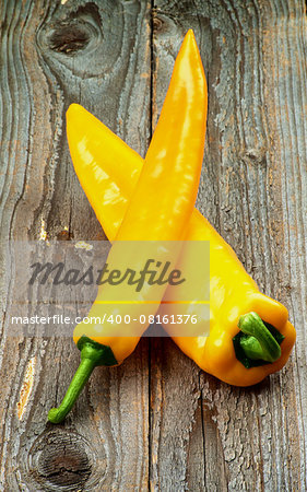 Arrangement of Perfect Ripe Yellow Ramiro Peppers with Green Tails isolated on Rustic Wooden background