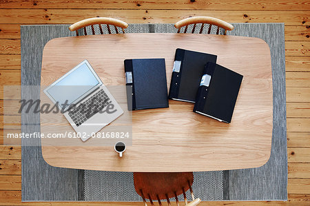 Laptop and binders on wooden table