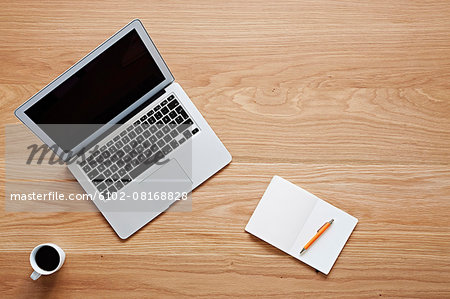 Laptop and notebook on wooden desk