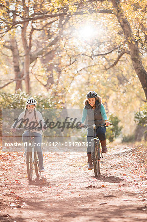 Mother and daughter bike riding on path in woods