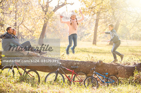 Family playing on fallen log in autumn woods