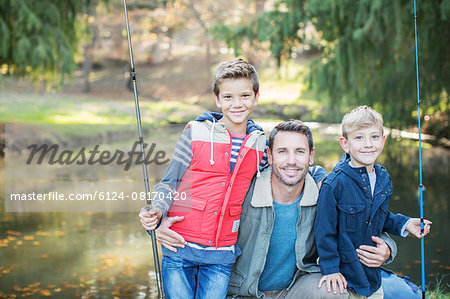 Portrait smiling father and sons with fishing rods