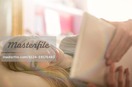 Portrait smiling teenage girl using digital tablet on bed
