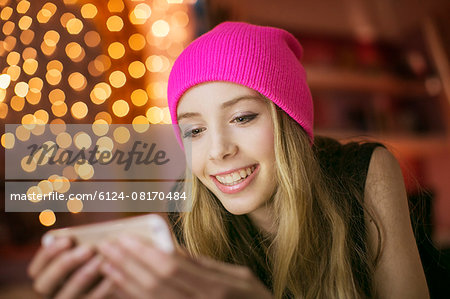 Teenage girl in pink beanie texting with cell phone