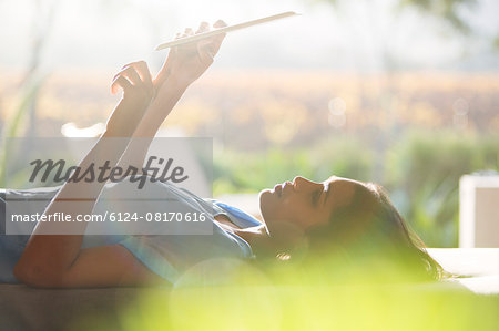 Woman laying and using digital tablet on patio