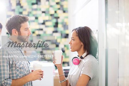 Creative business people with coffee and headphones talking in office