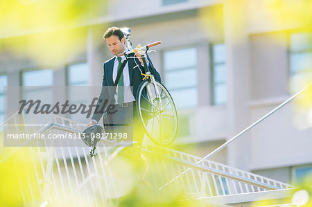 Businessman in suit carrying bicycle in city