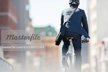 Businessman in suit and helmet riding bicycle in city