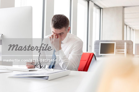 Tired businessman rubbing eyes at computer in office