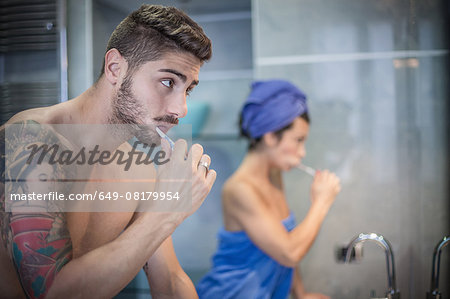 Young couple brushing teeth in bathroom
