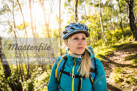 Young woman riding mountain bike through woods, Lake Como, Italy