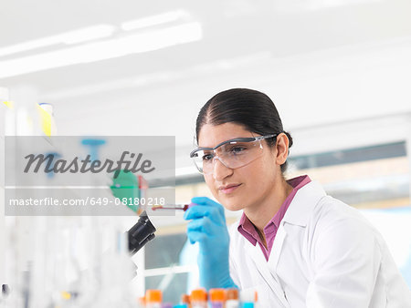 Young woman scientist viewing blood tube during clinical testing of medical samples in a laboratory