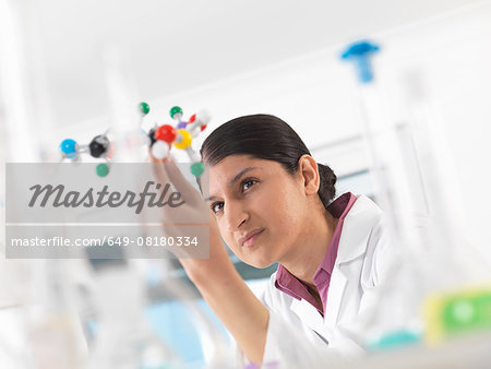 Female scientist in laboratory, viewing molecular model of a chemical formula