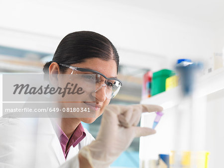 Female scientist viewing sample in eppendorf ahead of DNA testing in a laboratory.