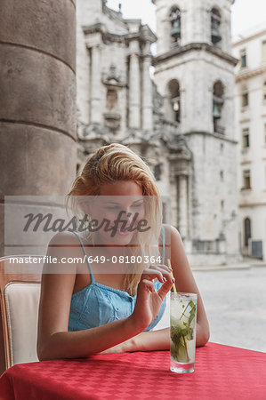 Young woman with a Mojito cocktail in a restaurant on the Plaza de la Cathedral of Havana, Cuba