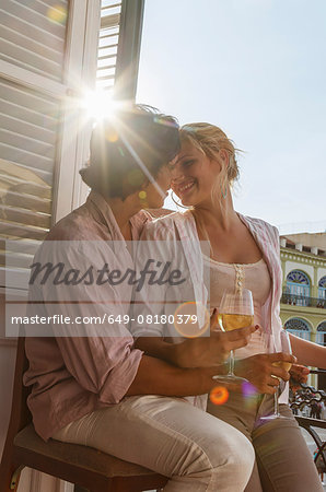 Romantic young couple drinking wine on restaurant balcony in Plaza Vieja, Havana, Cuba