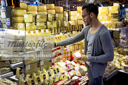 Young man selecting cheese in delicatessen market stall, Sao Paulo, Brazil