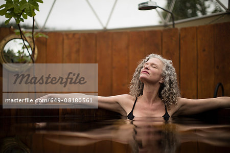Mature woman relaxing in hot tub at eco retreat