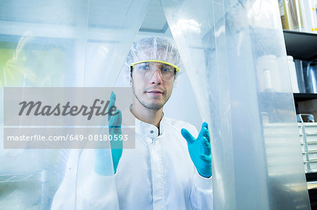 Portrait of male scientist behind plastic curtain in lab cleanroom
