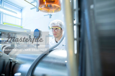 Male scientist reading equipment gauge in lab cleanroom