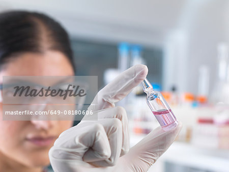 Female scientist testing medical drug ampule in laboratory