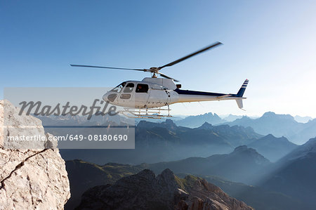 Helicopter transporting BASE jumpers to summit, Dolomites, Italy