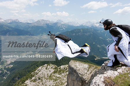 Two male BASE jumpers exiting from mountain top, Dolomites, Italy