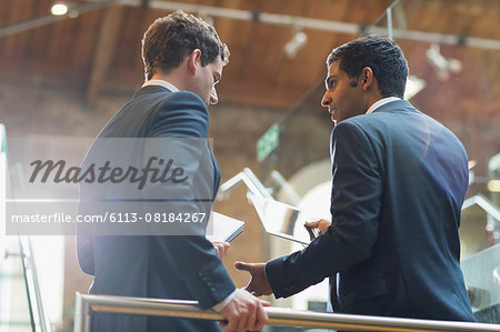 Businessmen with digital tablet talking in office Businessmen with digital tablet talking in office