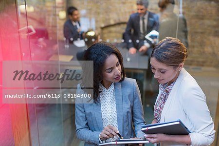 Businesswomen talking outside conference room meeting