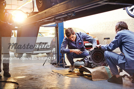 Mechanics examining part in auto repair shop