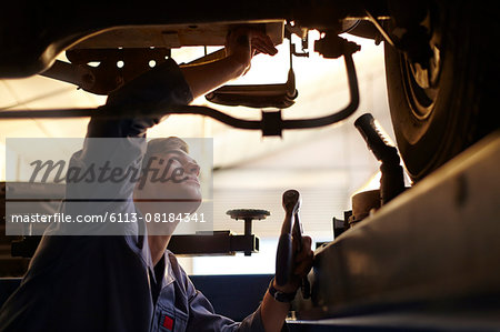 Mechanic working under car in auto repair shop