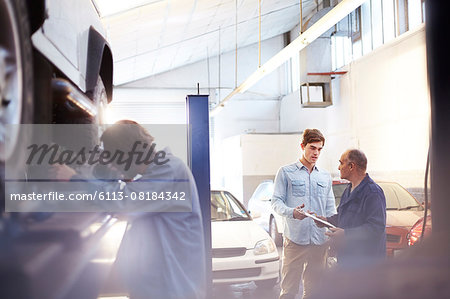 Mechanic speaking with customer in auto repair shop Mechanic speaking with customer in auto repair shop