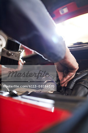 Close up mechanic arm reaching in car engine