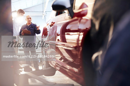 Mechanic with clipboard talking to customer in auto repair shop