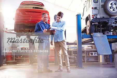 Mechanic with clipboard talking in auto repair shop Mechanic with clipboard talking in auto repair shop