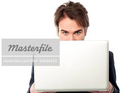 Serious male manager hiding face behind laptop