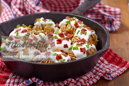 Hasselback potatoes with cheese, sour cream, bacon and green onion