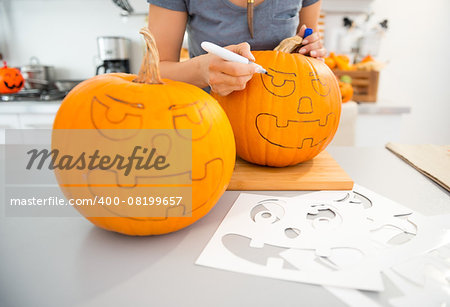 Close up on woman creating pumpkins Jack-O-Lantern for Halloween party in kitchen. Traditional autumn holiday