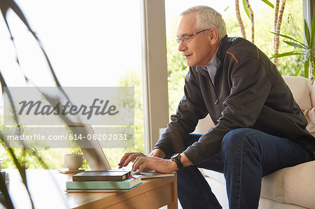 Senior man at home, using laptop
