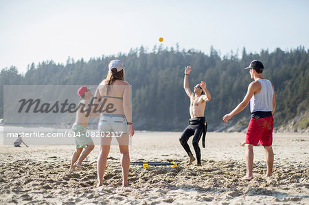 Four adult friends throwing and catching ball on Short Sands Beach, Oregon, USA